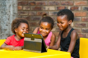 Three African Kids Playing Together On Tablet.